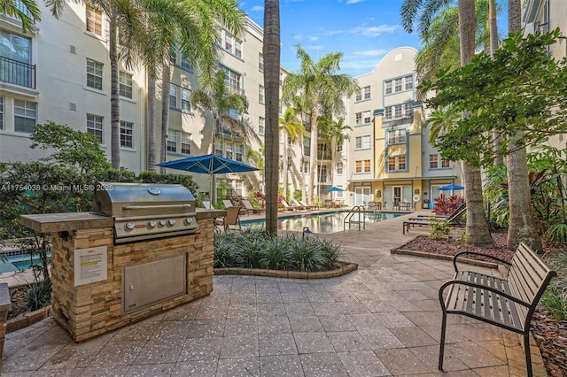 view of patio with exterior kitchen, grilling area, and a community pool