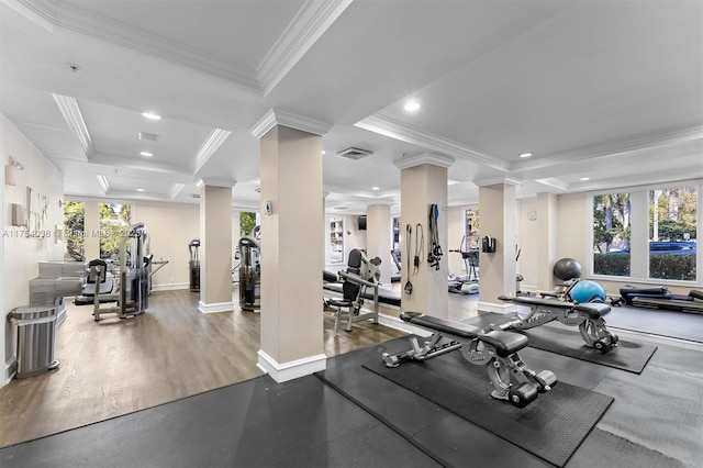 gym featuring wood finished floors, visible vents, ornate columns, a raised ceiling, and crown molding