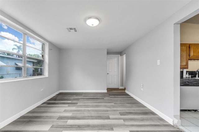 spare room with light wood-style floors, visible vents, and baseboards