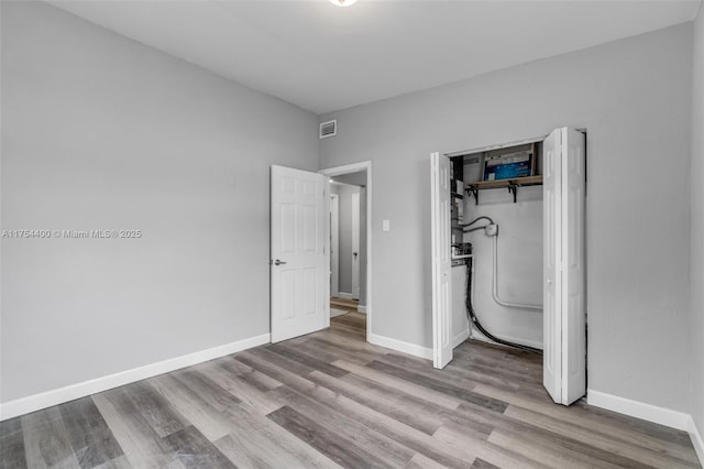 unfurnished bedroom featuring baseboards, visible vents, and wood finished floors