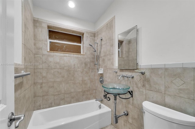 full bath featuring  shower combination, a sink, tile walls, and toilet