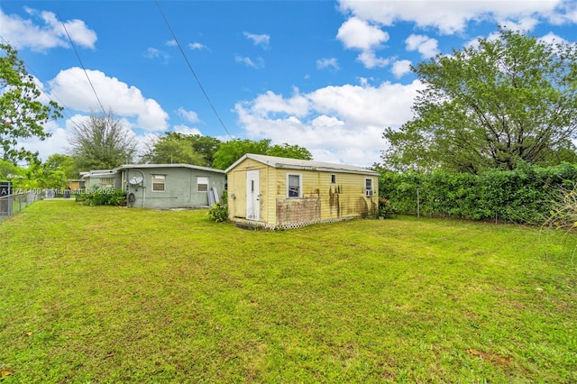 rear view of property featuring fence, an outbuilding, and a yard