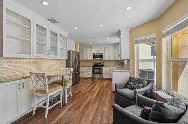 kitchen with stainless steel appliances, a sink, visible vents, white cabinets, and dark wood-style floors