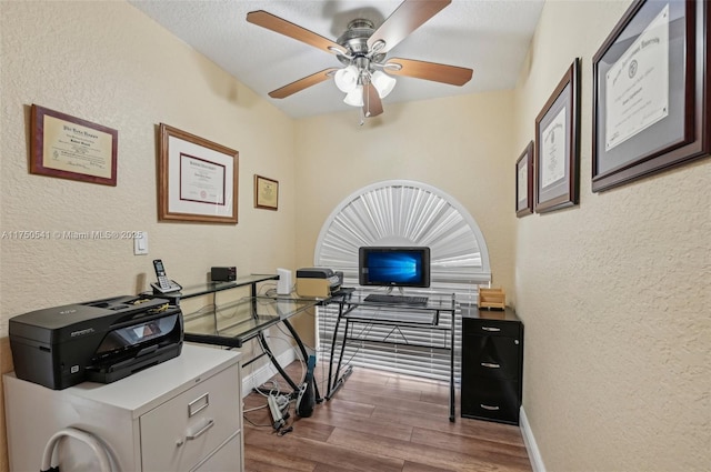 office space featuring baseboards, wood finished floors, and a textured wall