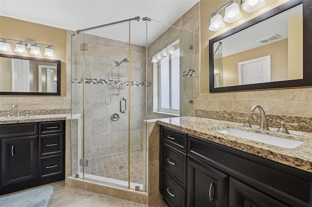 bathroom featuring a shower stall, visible vents, two vanities, and a sink