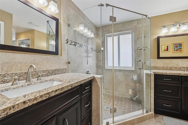 full bath with a shower stall, a sink, visible vents, and tile walls