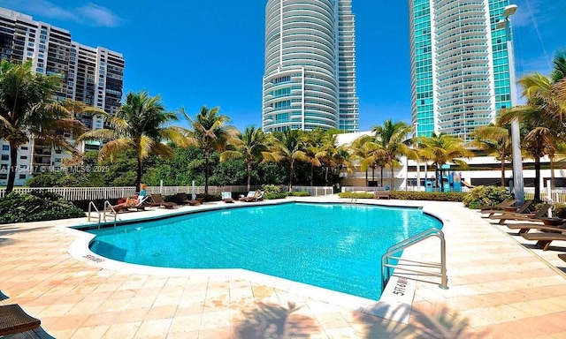 pool with a view of city, a patio, and fence