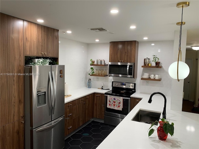 kitchen with open shelves, stainless steel appliances, light countertops, visible vents, and a sink