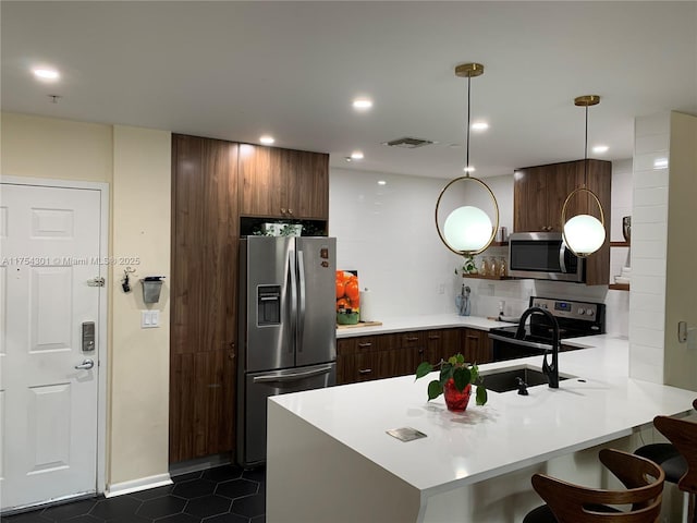 kitchen with stainless steel appliances, a peninsula, visible vents, light countertops, and decorative backsplash