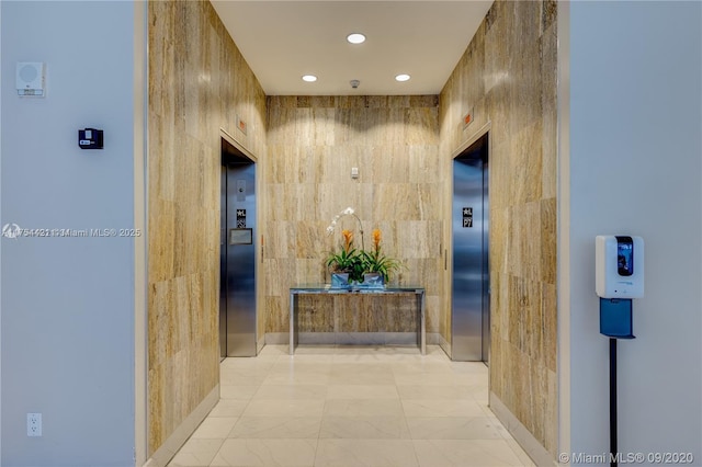 corridor featuring recessed lighting, elevator, and tile walls