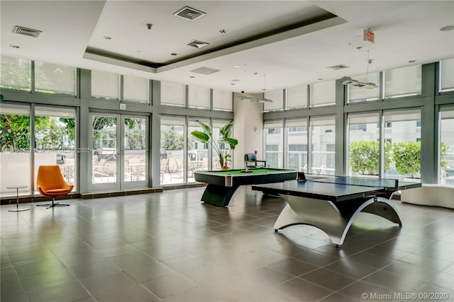 rec room featuring a wall of windows, a tray ceiling, and visible vents