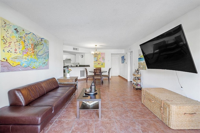 living room featuring a textured ceiling, an inviting chandelier, visible vents, and tile patterned floors