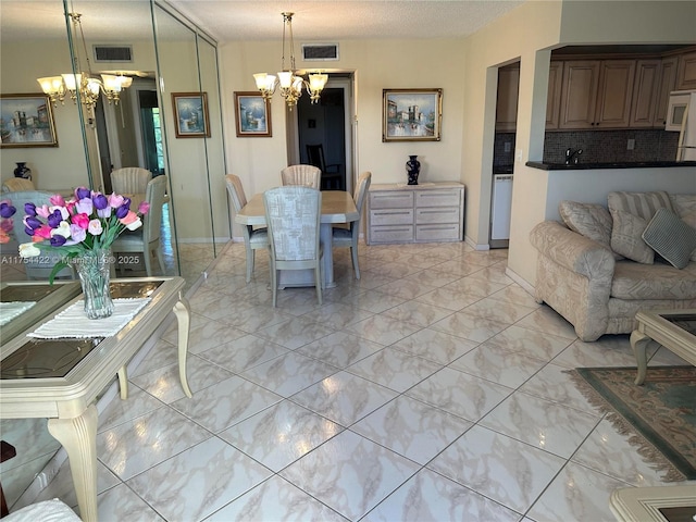 dining space with visible vents, a notable chandelier, a textured ceiling, and baseboards