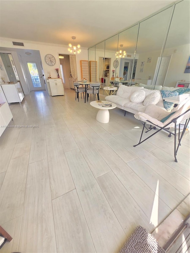 living area with visible vents, a notable chandelier, and wood finish floors