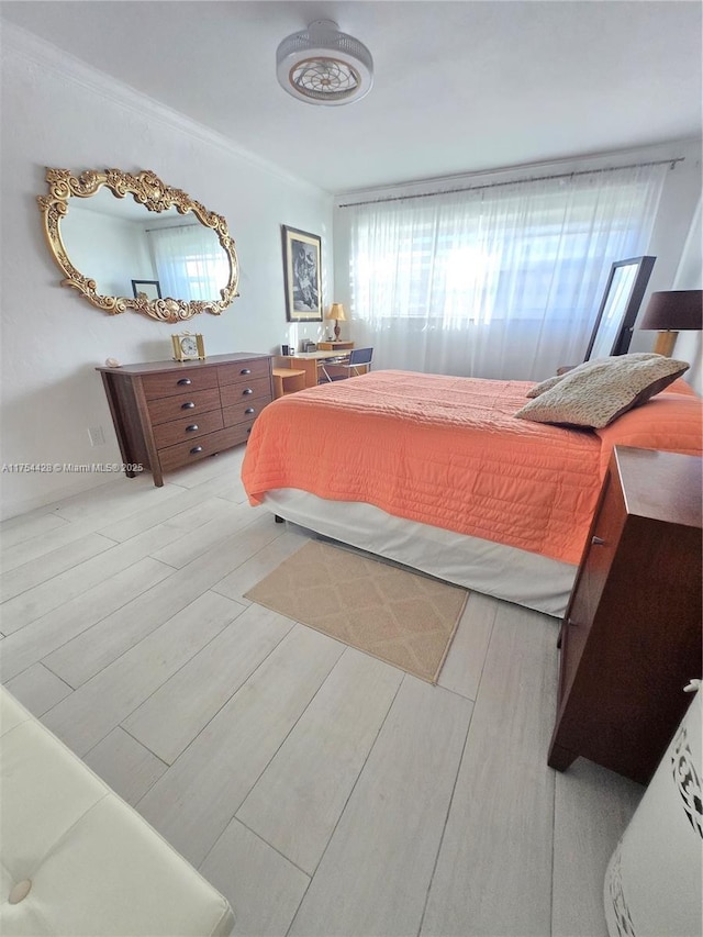 bedroom featuring crown molding and light wood finished floors