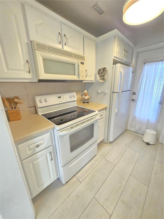 kitchen featuring light countertops, white appliances, visible vents, and white cabinets