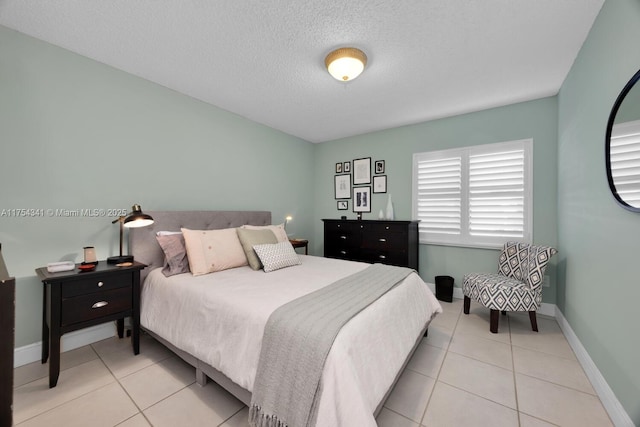 bedroom featuring a textured ceiling, baseboards, and light tile patterned floors