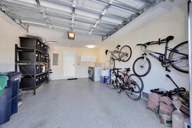 garage with washing machine and clothes dryer, electric panel, and a garage door opener