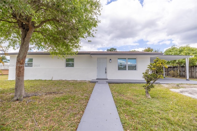 ranch-style home with a carport, a front lawn, fence, and stucco siding