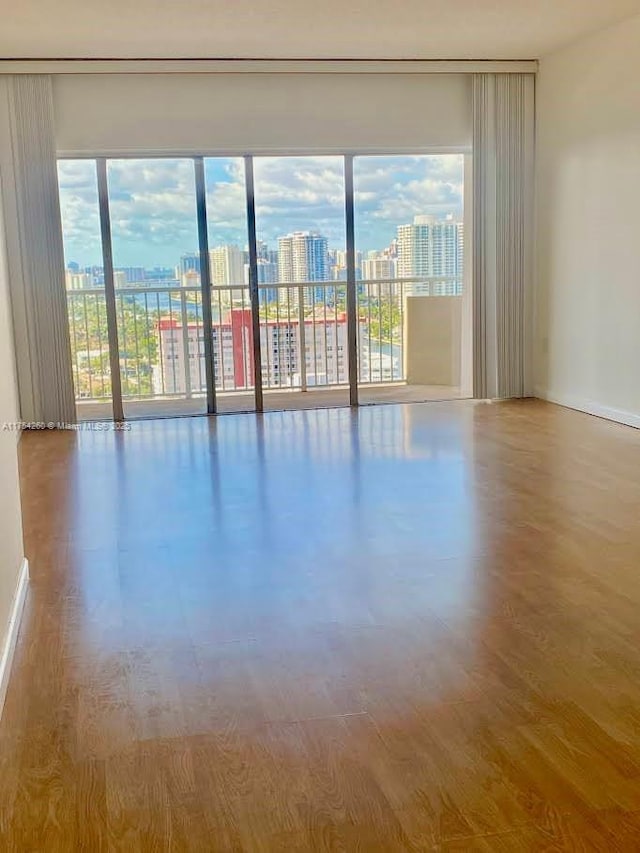 spare room featuring baseboards, wood finished floors, a wealth of natural light, and a city view