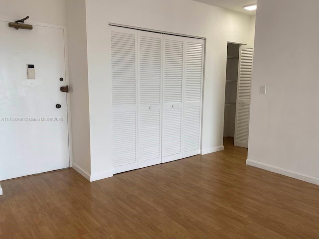 unfurnished bedroom featuring a closet, wood finished floors, and baseboards