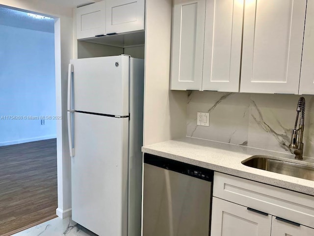 kitchen featuring decorative backsplash, freestanding refrigerator, white cabinetry, a sink, and dishwasher