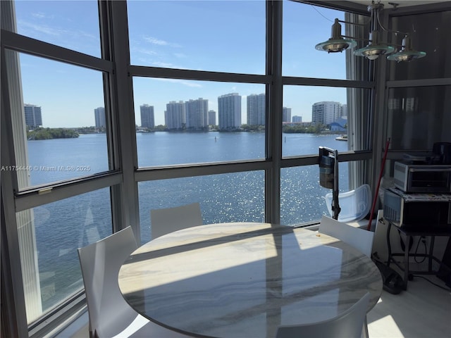 sunroom with a notable chandelier, a water view, and a city view