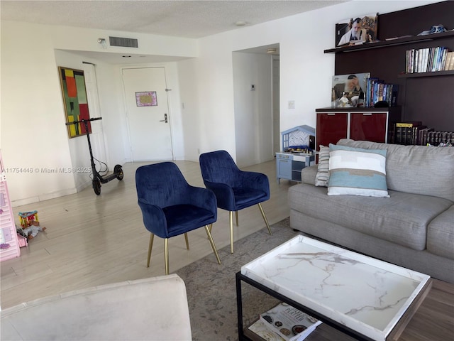 living room featuring a textured ceiling, wood finished floors, and visible vents