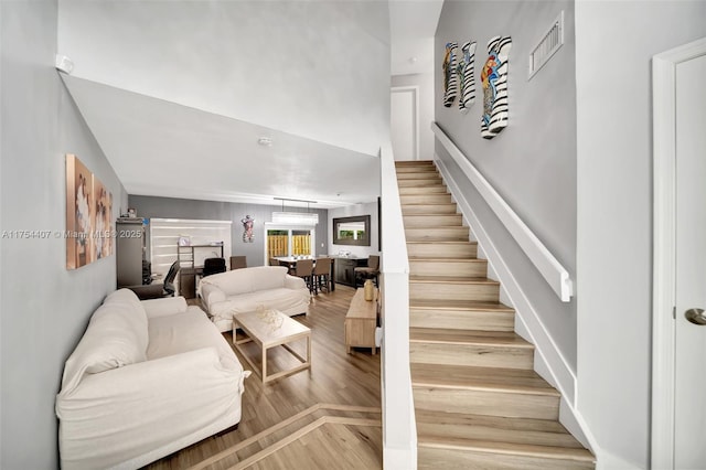 stairway featuring wood finished floors and visible vents