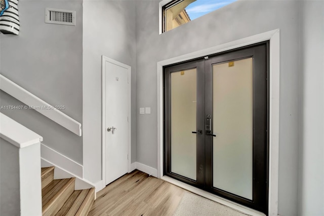 entrance foyer with baseboards, visible vents, wood finished floors, stairs, and french doors