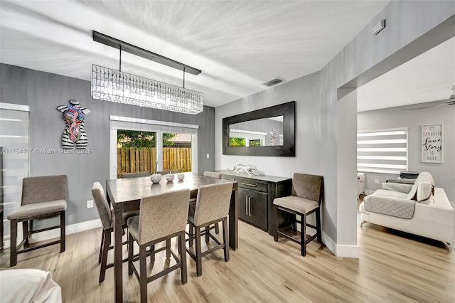 dining room with ceiling fan, light wood finished floors, visible vents, and baseboards