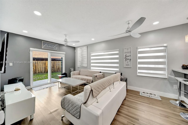 living room with plenty of natural light, baseboards, a ceiling fan, and wood finished floors