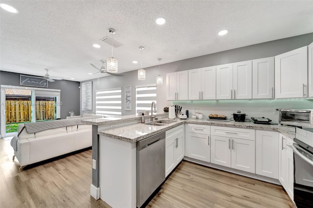 kitchen with open floor plan, oven, a peninsula, stainless steel dishwasher, and a sink