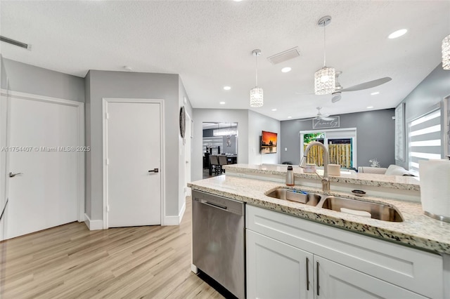 kitchen featuring visible vents, dishwasher, light wood-style flooring, pendant lighting, and a sink