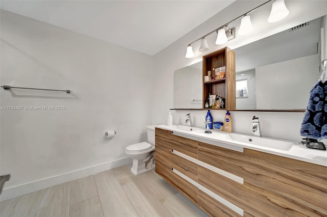 bathroom with toilet, a sink, visible vents, and baseboards