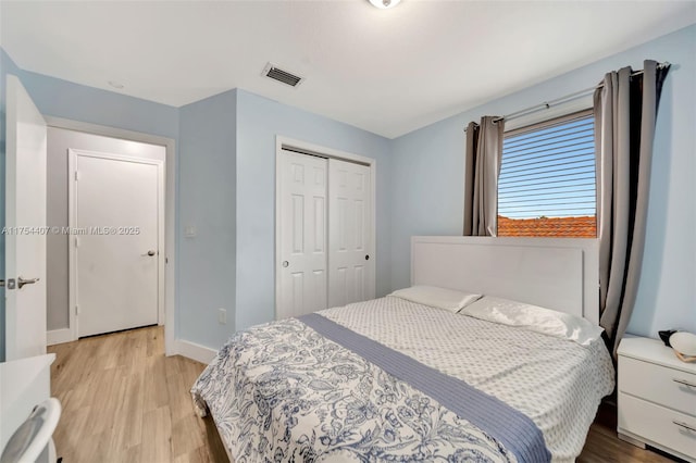 bedroom with light wood finished floors, a closet, visible vents, and baseboards