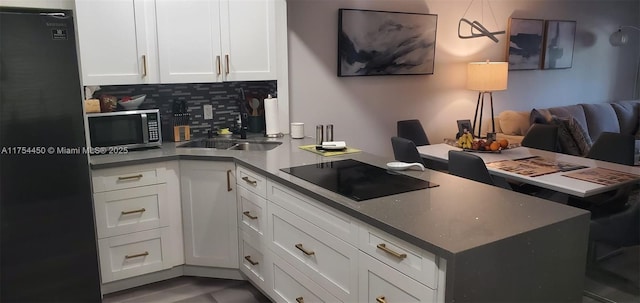 3160 Holiday Springs Blvd Unit 7-112, Margate, FL 33063 - kitchen featuring white cabinetry, backsplash, a sink, a peninsula, and black appliances