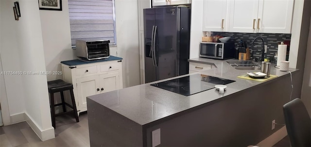 3160 Holiday Springs Blvd Unit 7-112, Margate, FL 33063 - kitchen featuring a sink, white cabinetry, a peninsula, black appliances, and decorative backsplash