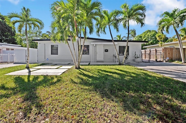 rear view of property featuring fence, a lawn, and stucco siding