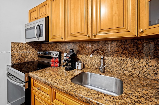 kitchen featuring decorative backsplash, appliances with stainless steel finishes, brown cabinets, light stone countertops, and a sink