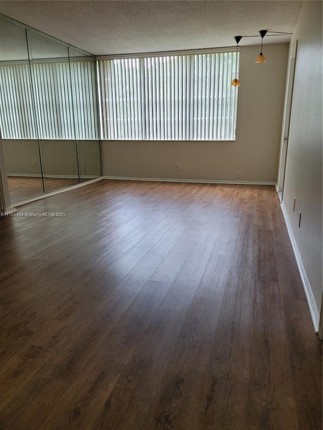 spare room with a textured ceiling, baseboards, and wood finished floors