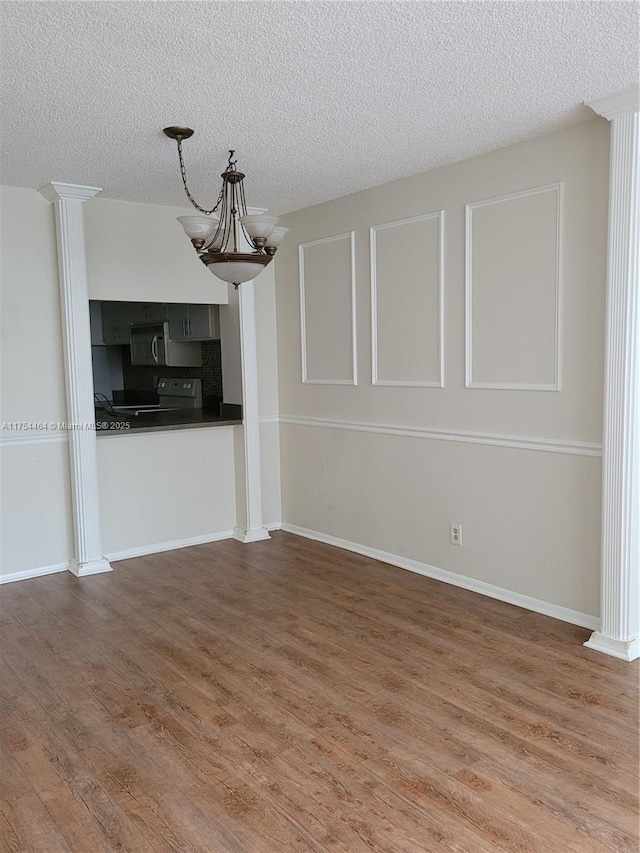 unfurnished living room featuring a textured ceiling, baseboards, and wood finished floors