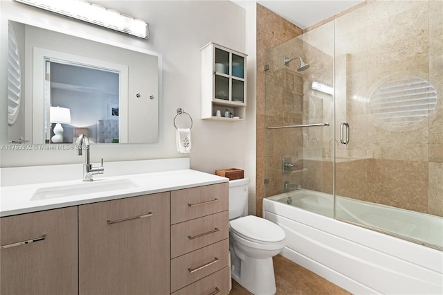 bathroom featuring combined bath / shower with glass door, vanity, and toilet