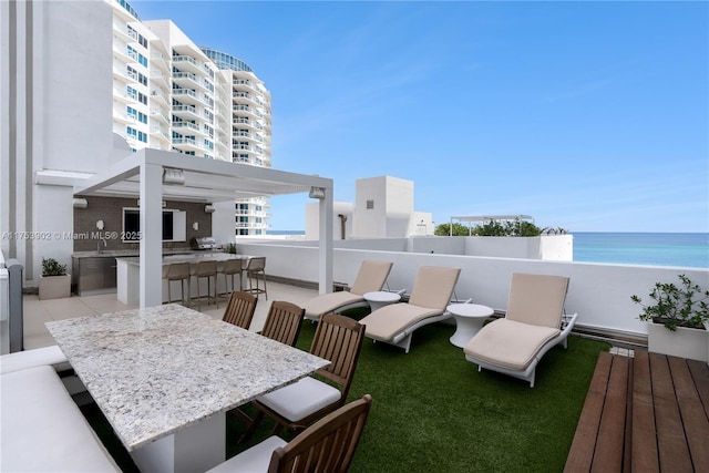 view of patio / terrace featuring a water view, outdoor dining area, outdoor dry bar, and exterior kitchen