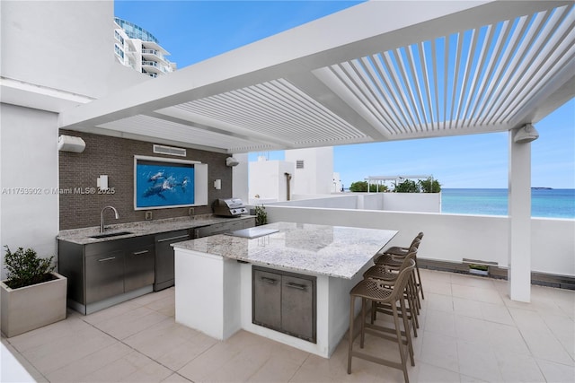 view of patio / terrace with an outdoor kitchen, a view of the beach, outdoor wet bar, a water view, and a sink