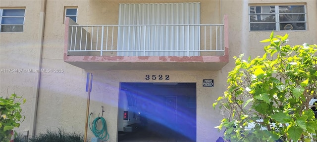 view of exterior entry featuring a balcony and stucco siding