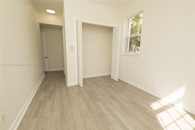 unfurnished bedroom with light wood-style flooring, baseboards, and a closet