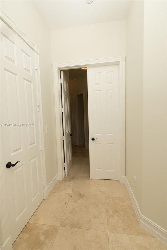 hall featuring light tile patterned floors and baseboards