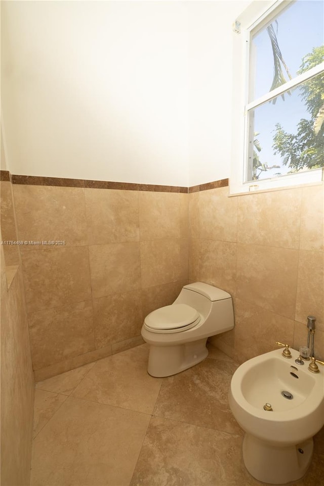 half bathroom with a bidet, toilet, and tile walls