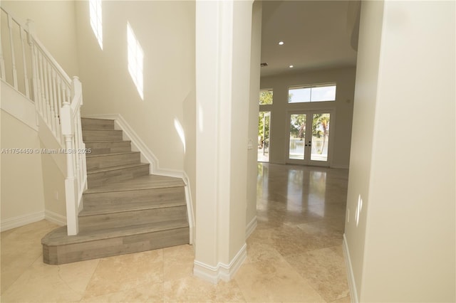 staircase featuring baseboards, french doors, a high ceiling, and recessed lighting